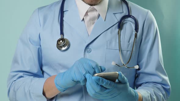 Doctor in Professional Medical Suit and Blue Gloves Checking Temperature By Digital Thermometer