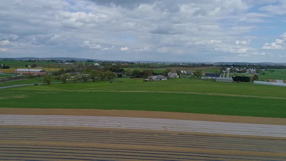 A Drone View of Amish Farmlands and Homesteads and Approaching Amish Teens Playing Volleyball on a S