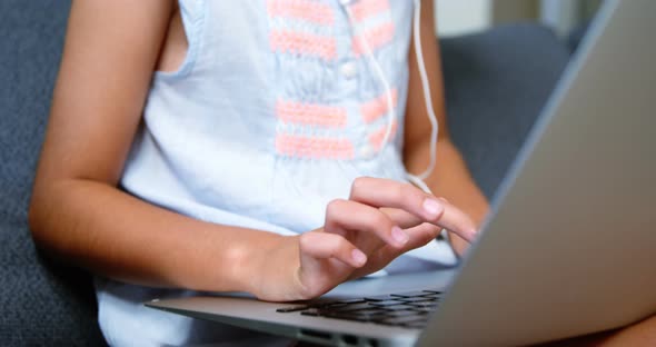 Girl with headphones using laptop in living room