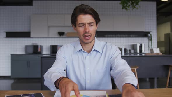 Caucasian businessman having video chat going through paperwork in workplace kitchen