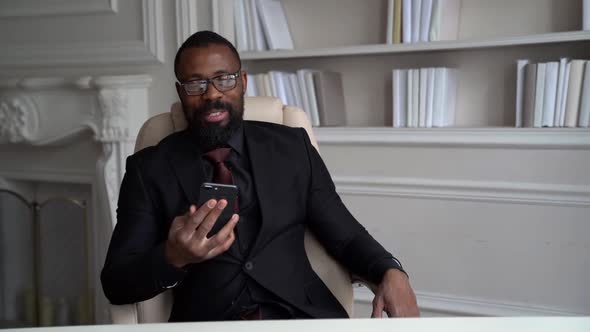 African-American Bearded Man in a Black Suit, Shirt, Stylish Glasses. A Businessman Is Working on a