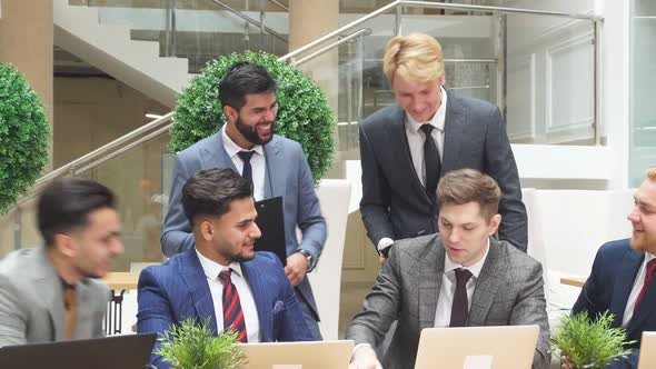 European and Arabic Young Businessmen Sit Communicating, Look at Each Other, Have Conversation About