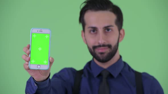 Face of Happy Young Bearded Persian Businessman Showing Phone