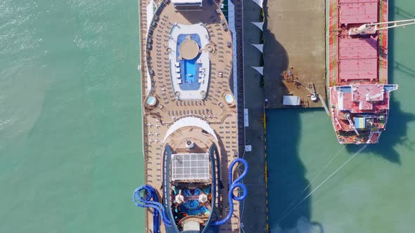 Aerial top down shot of luxury cruise ship with private swimming pool and chute beside docking indus