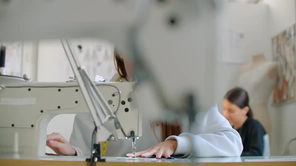 Front View Of Female Fashion Designer Working With Sewing Machine In Workshop