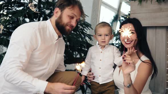 Mother and Father Holding Sparkler While Their Cute Child is Looking at Light