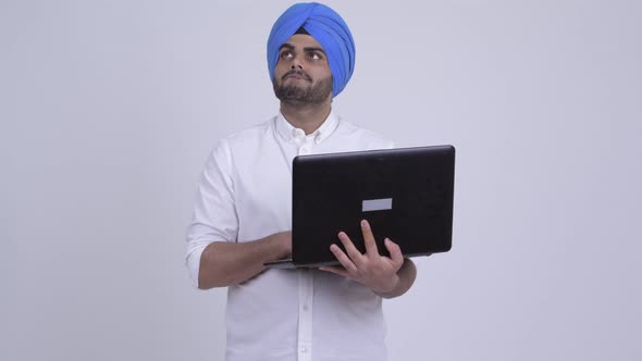 Young Bearded Indian Sikh Man Thinking While Using Laptop