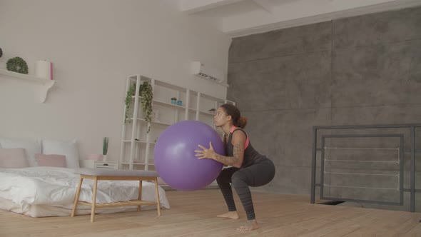 African American Woman Doing Squat with Fitball