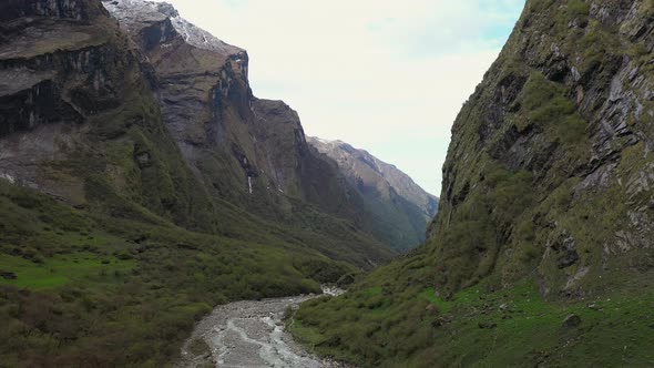 Aerial drone footage going through a valley and over a creek in the Annapurna mountains