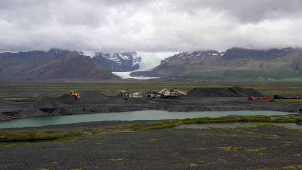 Iceland glacier with construction vehicles in foreground with drone video moving forward.