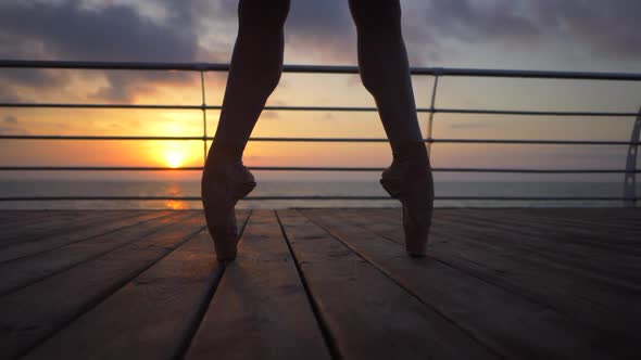 Close Up of a Ballet Dancer's Feet As She Practices Pointe Exercises on the Wooden Embankment Near