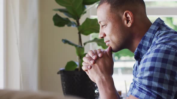 Side view of thoughtful biracial man sitting and looking outside window