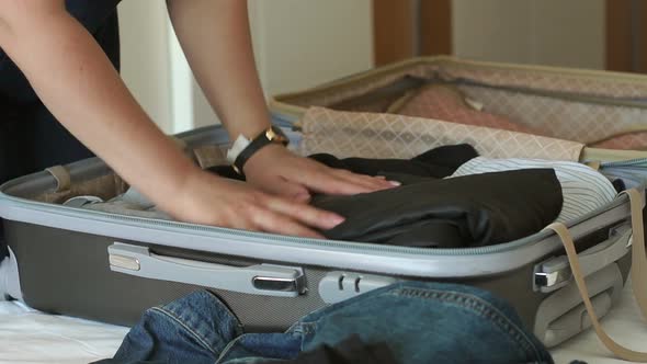 Closeup of the Girl Packing a Suitcase on the Bed in the Bedroom