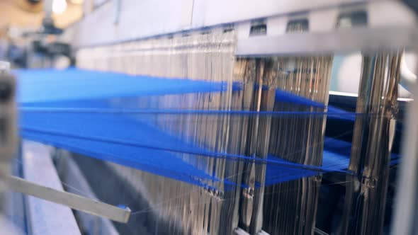 Close Up of Threads Being Woven Into Fabric By a Machine