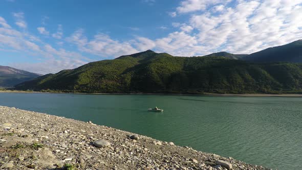 Man in Boat Sailing Down River on a Sunny Day, Serene Mountain Landscape, Travel