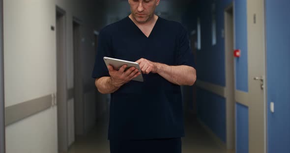 A Doctor Looks Up From the Tablet and Looks at the Camera with a Smile