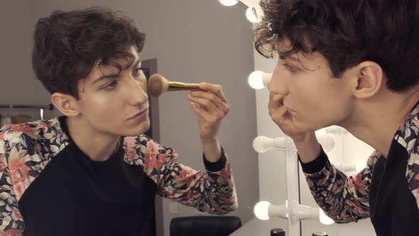 Closeup Androgynous Man Applying Powder with a Brush To His Face