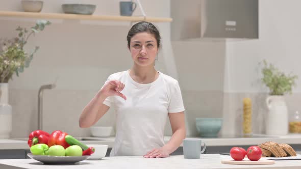 Indian Woman Showing Thumbs Down While Standing in Kitchen