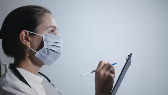 Female Doctor In Medical Mask Makes Notes
