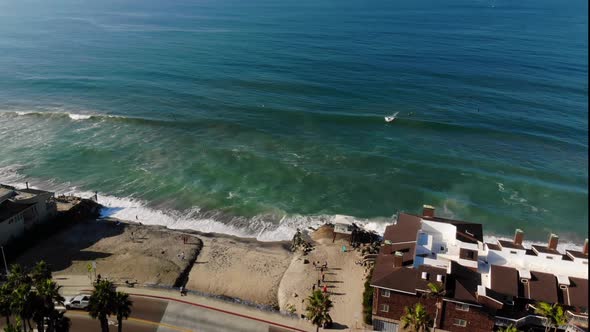 Aerial of a surfer catching a wave off a private beach with homes