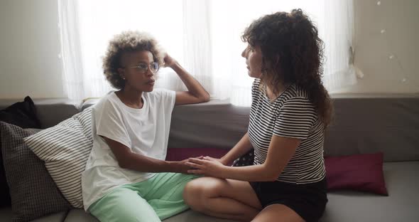 Two Multiethnic Lesbians Talking Affectionately on the Sofa at Home