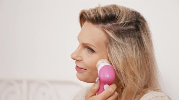 Smiling Caucasian Woman Using Electric Facial Cleansing Brush Closeup