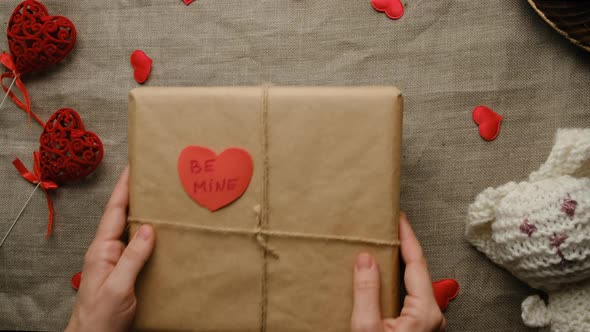 Female Hands Puts Valentines Day Present on Table