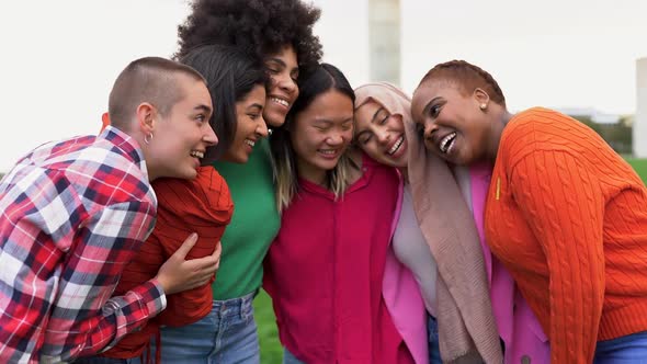 Beautiful diverse women hugging each other at city park while smiling on camera