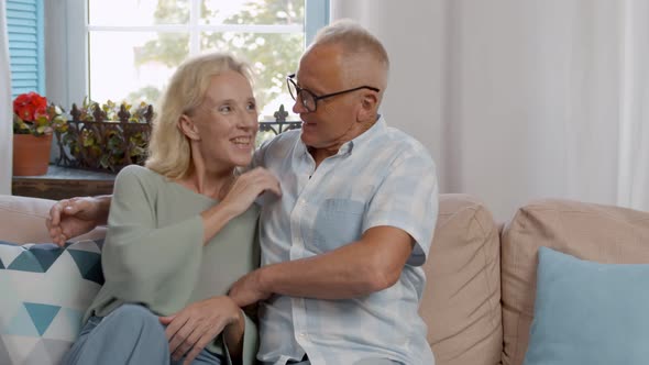 Retired Mature Couple Sitting on Couch Together and Relaxing