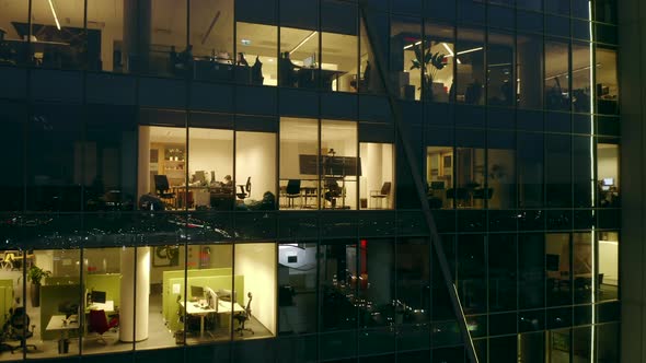 Aerial View of a Night Skyscraper with Siluets of People Working in Offices