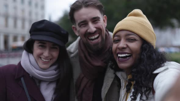 Three Young Adult Friends Taking Selfie Portrait with Mobile Phone in City