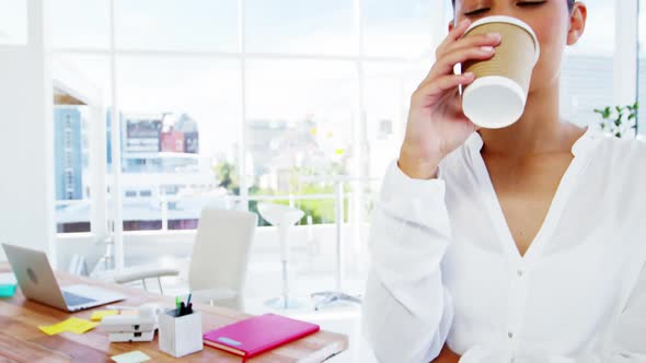 Woman sipping coffee with office background