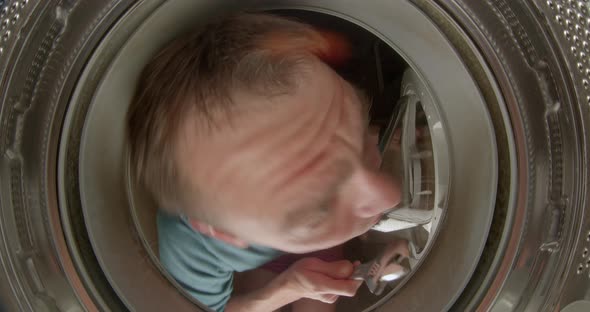 Cheerful Man in Washing Machine Holding Key and Pliers with Hands