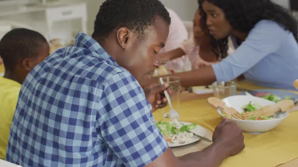 Happy african american father eating lunch with family at home