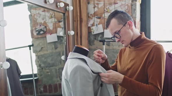 Tailor Fixing Jacket and Looking at Camera