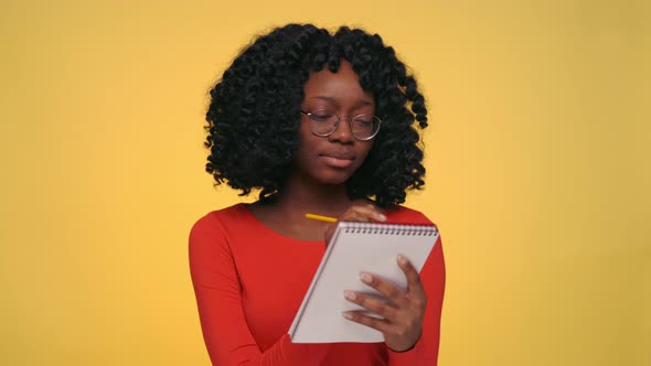 Thoughtful Black Woman Writing in Copybook at Studio