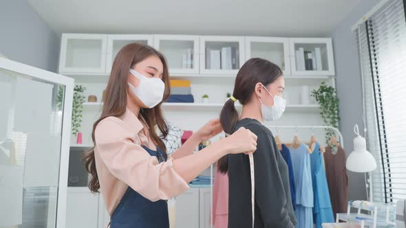 Asian young tailor woman measure customer's body to making her new clothes.