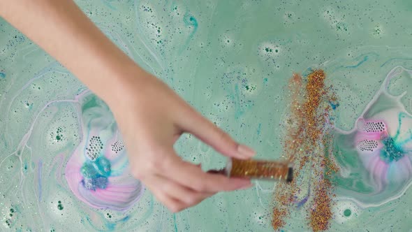 Pouring Gold Glitter Into Water with Dissolved Bath Closeup