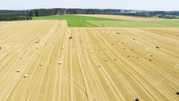 Aerial Drone Shot  a Field with a Tractor and Hay Bales in a Rural Area on a Sunny Day