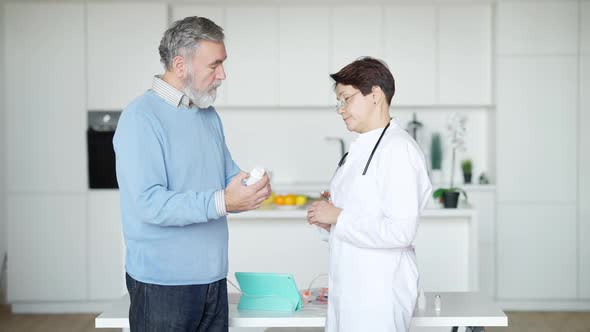 Side View of Positive Caucasian Doctor and Patient Shaking Hands After Consultation Indoors