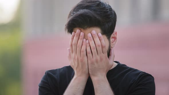Scared Upset Middle Eastern Bearded Young Man Wearing Black Tshirt Cover Face Feel Frightened