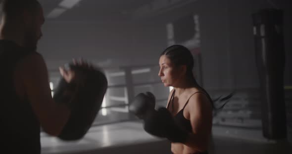 Young Woman Athlete in Boxing Gloves and Sport Clothes is Boxing With Her Skillful Trainer