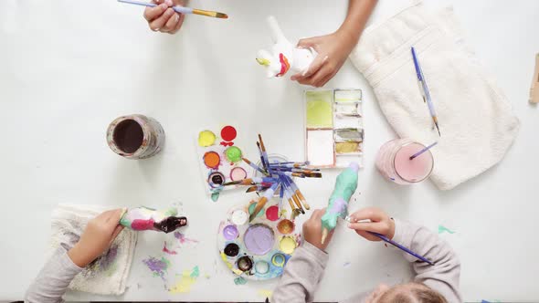 Step by step. Little girls painting paper mache unicorn with acrylic paint.