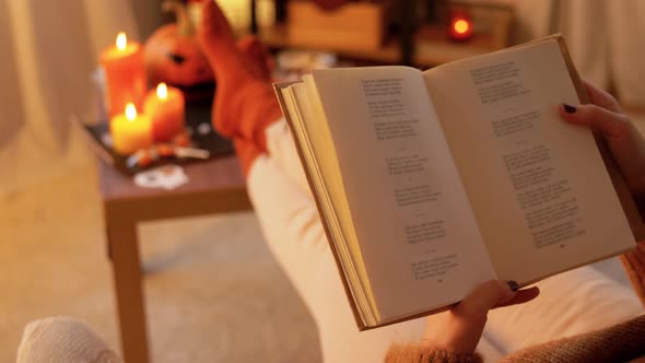 Young Woman Reading Book at Home on Halloween