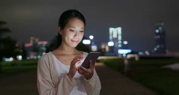 Woman use of mobile phone in city at night