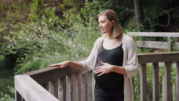 Pregnant Woman Walking Along Terrace Near the Mountain Lake.