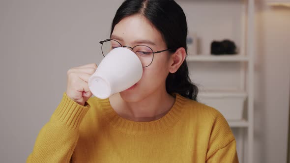 Young Asian female having a cup of coffee in the home office.