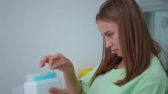 Side View Portrait of Focused Genius Young Female Scientist Checking Test Tubes in Box in Laboratory