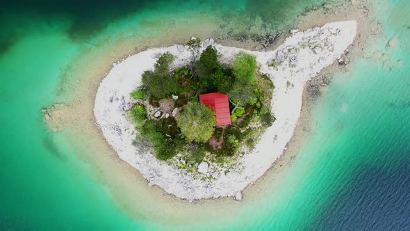 Log cabin with red roof on island in Eibsee lake, Bavaria, Germany