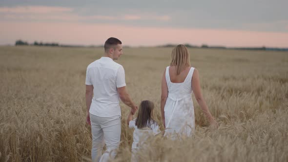 Slow Motion Happy Family of Farmers with Child are Walking on Wheat Field